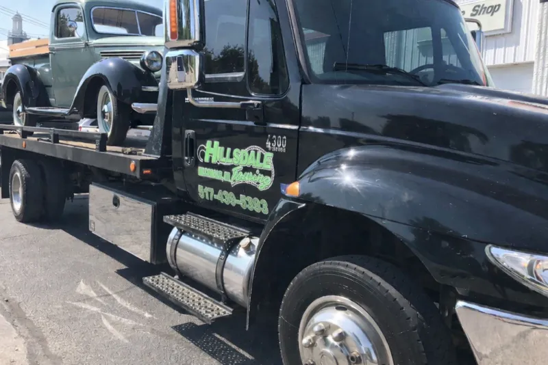 Hillsdale Towing flatbed hauling a vintage vehicle