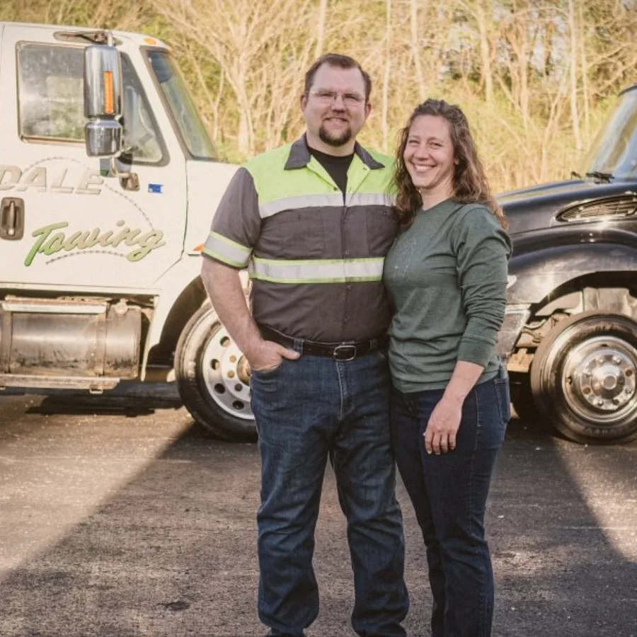 The owners of Hillsdale Towing standing with the company's trucks